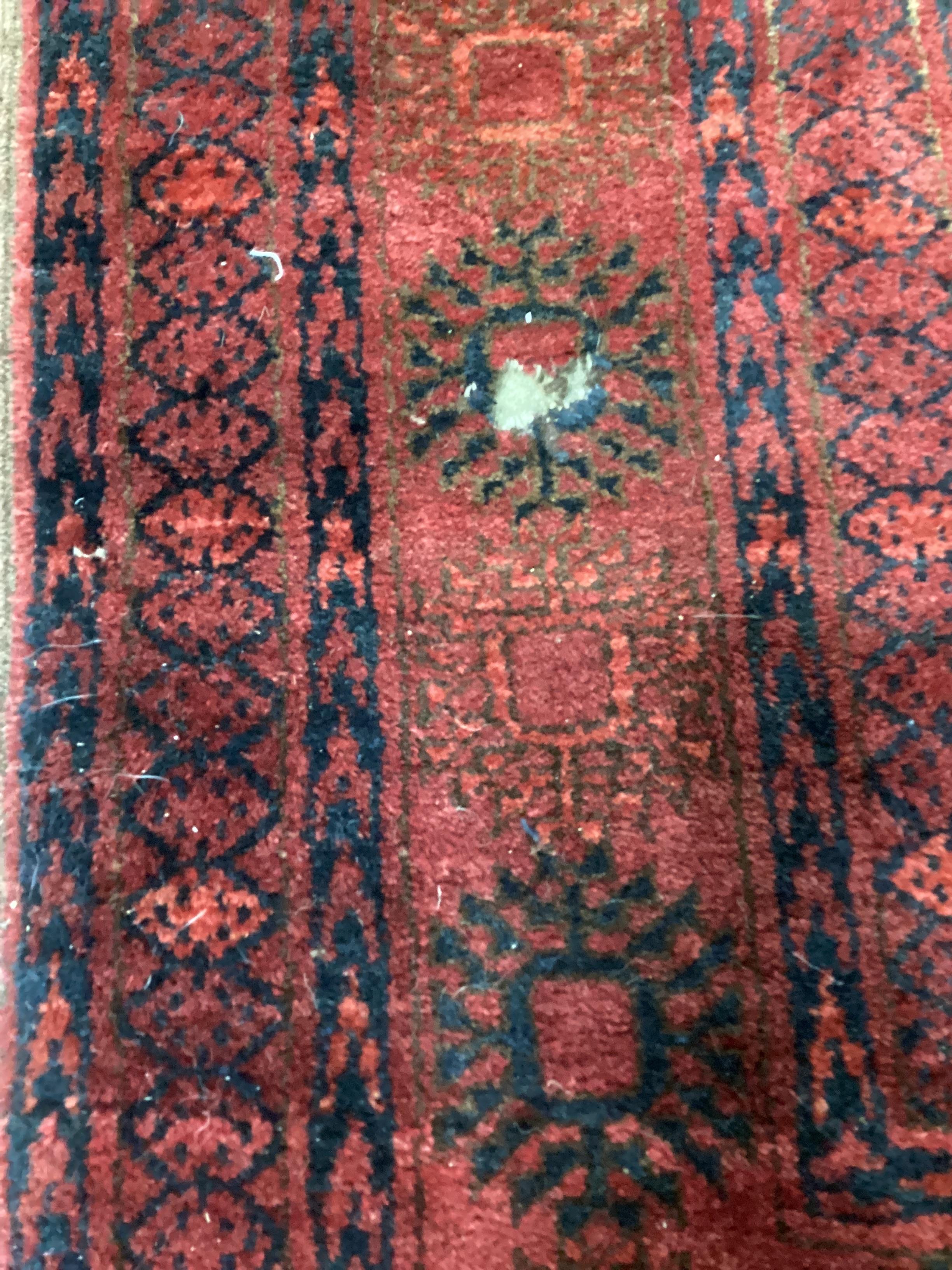 A Bokhara red ground carpet, worn and holed, 286 x 214cm